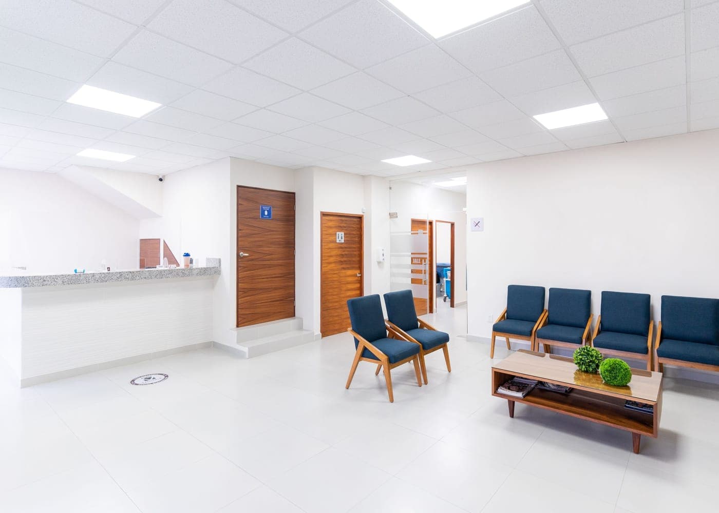 Salle d'attente de cabinet médical aux sièges bleus, sol clair et fraîchement lavé