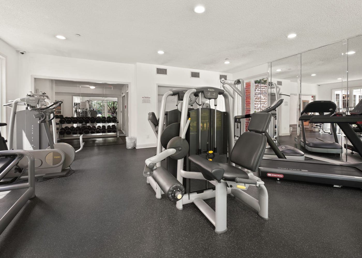 Plateau de musculation et tapis de course dans une salle éclairée, machines alignées